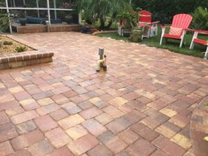 A nice paver patio with a yard and chairs around it