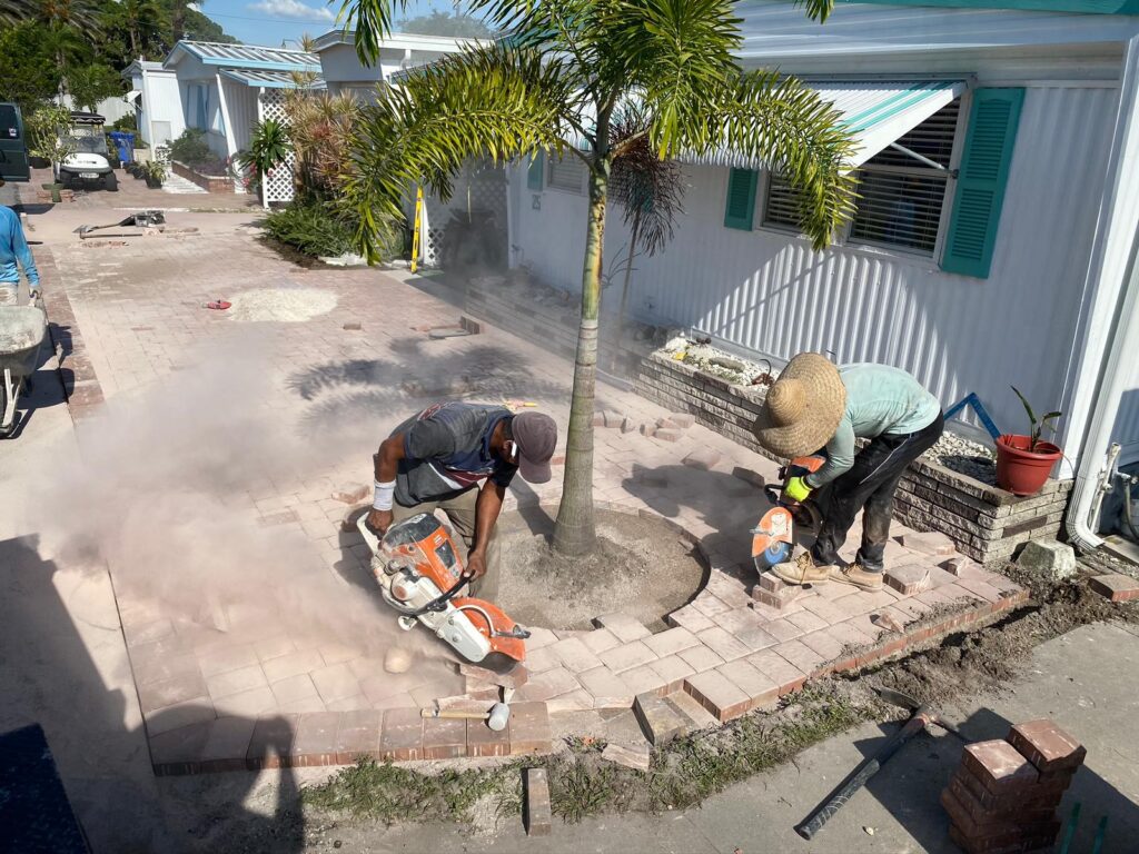 Two workers in a patio paver cutting brick pavers with mansory saws