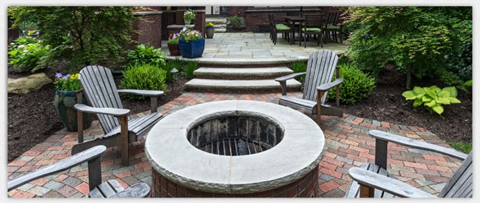 A patio with a fire pit on the center and surrounded by four chairs