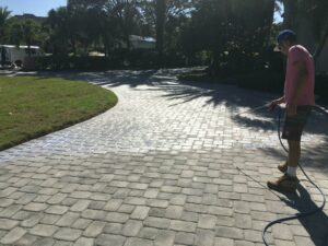 Paver patio being cleaned by a man with a pressure washer