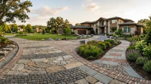 A wide residential driveway showcasing different types of pavers integrated into a modern landscape design under sunlight.