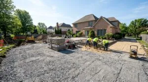 Wide view of a backyard construction site showing a leveled gray paver base prepared for a new patio installation.