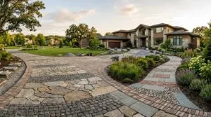 A wide residential driveway showcasing different types of pavers integrated into a modern landscape design under sunlight.